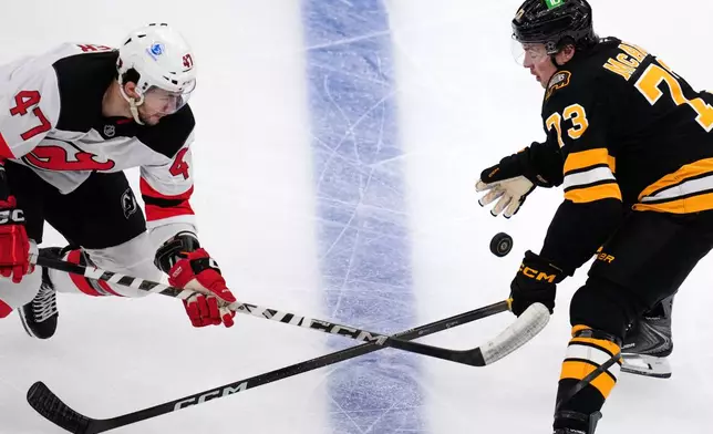 Boston Bruins defenseman Charlie McAvoy (73) and New Jersey Devils left wing Paul Cotter (47) battle for the puck during the second period of a hockey game, Tuesday, April 14, 2026, in Boston. (AP Photo/Charles Krupa)
