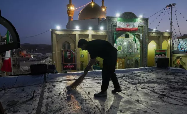 A worker cleans an area within the Grand Hosseiniyeh complex, with the mosque visible in the background, that officials say was hit by U.S.-Israeli airstrikes Tuesday in Zanjan, Iran, Saturday, April 4, 2026. (AP Photo/Francisco Seco)