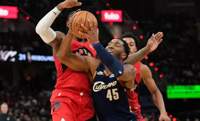 Cleveland Cavaliers guard Donovan Mitchell (45) drives past Toronto Raptors forward RJ Barrett, left, in the second half in Game 2 of a first-round NBA basketball playoffs series in Cleveland, Monday, April 20, 2026. (AP Photo/Sue Ogrocki)