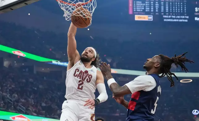 Cleveland Cavaliers guard Max Strus (2) dunks next to Washington Wizards guard Jamir Watkins (5) in the first half of an NBA basketball game in Cleveland, Sunday, April 12, 2026. (AP Photo/Sue Ogrocki)