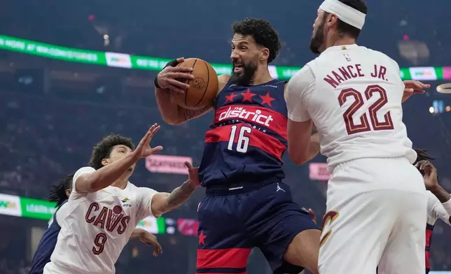Washington Wizards forward Anthony Gill (16) grabs a rebound between Cleveland Cavaliers guard Craig Porter Jr. (9) and forward Larry Nance Jr. (22) in the first half of an NBA basketball game in Cleveland, Sunday, April 12, 2026. (AP Photo/Sue Ogrocki)