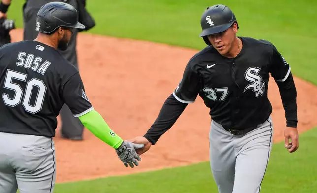 Chicago White Sox' Dustin Harris (37) celebrates with Lenyn Sosa (50) after scoring on a wild pitch by Kansas City Royals relief pitcher John Schreiber during the seventh inning of a baseball game Sunday, April 12, 2026, in Kansas City, Mo. (AP Photo/Charlie Riedel)