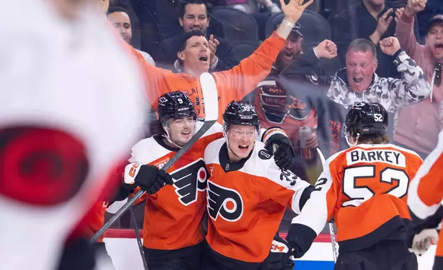 Philadelphia Flyers right winger Matvei Michkov, center, celebrates after his goal with defenseman Jamie Drysdale, left, and center Denver Barkey, right, during the second period of an NHL hockey game against the Carolina Hurricanes, Monday, April 13, 2026, in Philadelphia. (AP Photo/Chris Szagola)
