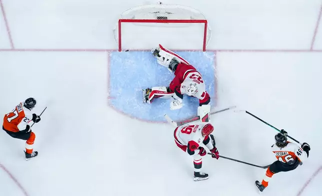 Philadelphia Flyers center Trevor Zegras, right, scores against Carolina Hurricanes goalie Brandon Bussi, center top, during the second period of an NHL hockey game, Monday, April 13, 2026, in Philadelphia. (AP Photo/Chris Szagola)