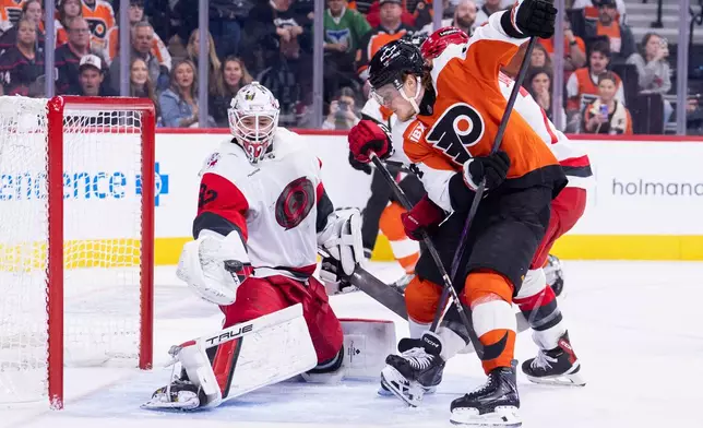 Carolina Hurricanes goalie Brandon Bussi, left, makes the glove save in front of Philadelphia Flyers right winger Owen Tippett, right, during the second period of an NHL hockey game, Monday, April 13, 2026, in Philadelphia. (AP Photo/Chris Szagola)