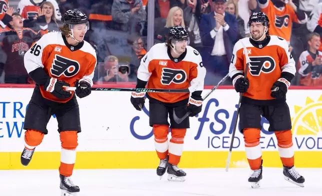 Philadelphia Flyers center Trevor Zegras, left, celebrates with defenseman Jamie Drysdale, center, and left winger Noah Cates, right, after his goal during the second period of an NHL hockey game against the Carolina Hurricanes, Monday, April 13, 2026, in Philadelphia. (AP Photo/Chris Szagola)