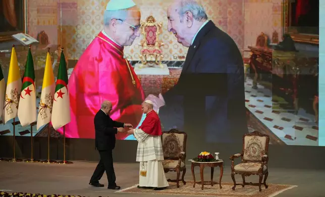 Pope Leo XIV is greeted by President Abdelmadjid Tebboune, left, at the Djamaa el Djazair Conference Center during a meeting with Algerian authorities, members of the civil society, and diplomatic corps in Algiers, Monday, April 13, 2026, on the first day of an 11-day apostolic journey to Africa. (AP Photo/Andrew Medichini)