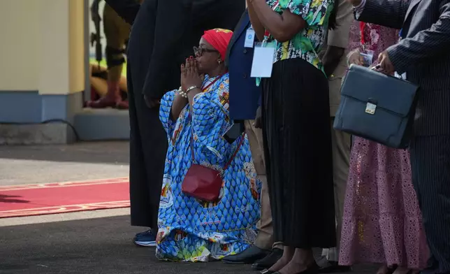 A woman kneels in prayer as Pope Leo XIV arrives at Yaounde-Nsimalen International Airport, Cameroon, Wednesday, April 15, 2026, on the third day of an 11-day apostolic journey to Africa. (AP Photo/Andrew Medichini)