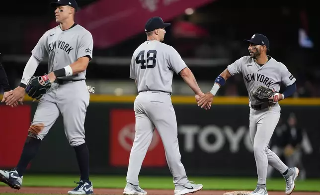 New York Yankees first baseman Paul Goldschmidt celebrates a win over the Seattle Mariners with shortstop José Caballero, right, and right fielder Aaron Judge, left, after a baseball game, Wednesday, April 1, 2026, in Seattle. (AP Photo/Lindsey Wasson)