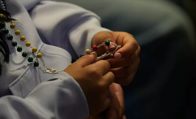 A woman holds a rosary as she attends a vigil for peace lead by Pope Leo XIV inside St. Peter's Basilica at the Vatican, Saturday, April 11, 2026. (AP Photo/Gregorio Borgia)