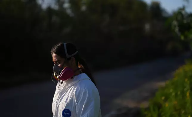 Maddie Tibayan pauses while wearing a respirator while collecting a water sample of the Tijuana River, as part of a research team from the University of California, San Diego, Wednesday, March 11, 2026, in San Diego. (AP Photo/Gregory Bull)