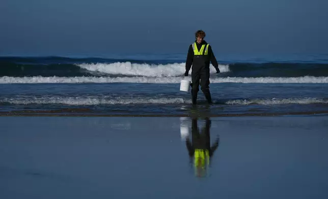 Trent Fry, part of a research team from the University of California, San Diego, takes a sample of seawater Wednesday, March 11, 2026, in Imperial Beach, Calif. (AP Photo/Gregory Bull)