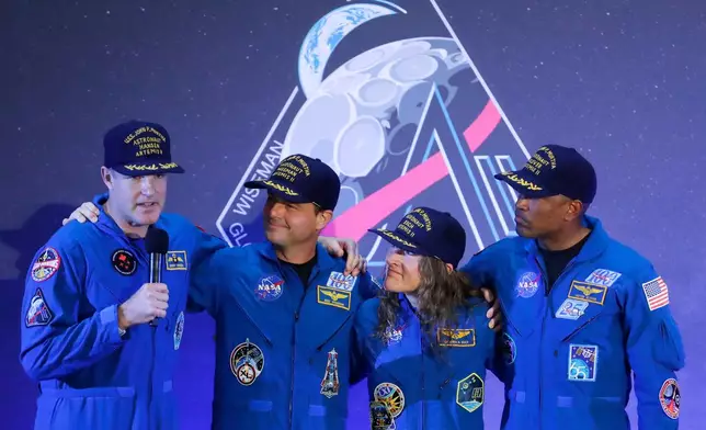 The Artemis II crew, from left, Jeremy Hansen, Reid Wiseman, Christina Koch and Victor Glover gather with Hansen as he speaks during a crew return event Saturday, April 11, 2026, at Ellington Field in Houston. (AP Photo/Michael Wyke)