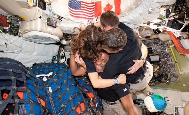 In this image provided by NASA, The Artemis II crew, clockwise from left, Mission Specialist Christina Koch, Mission Specialist Jeremy Hansen, Commander Reid Wiseman, and Pilot Victor Glover, take time out for a group hug inside the Orion spacecraft on their way home on Wednesday, April 7, 2026. (NASA via AP)