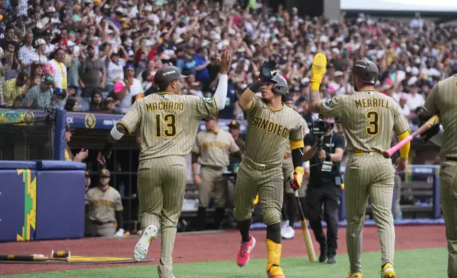 San Diego Padres' Manny Machado, left, is congratulated after scoring against the Arizona Diamondbacks during the seventh inning of a baseball game in Mexico City, Saturday, April 25, 2026. (AP Photo/Fernando Llano)