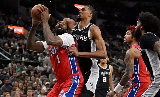 Philadelphia 76ers center Andre Drummond, left, tangles with San Antonio Spurs center Victor Wembanyama during the first half of an NBA basketball game, Monday, April 6, 2026, in San Antonio. (AP Photo/Darren Abate)