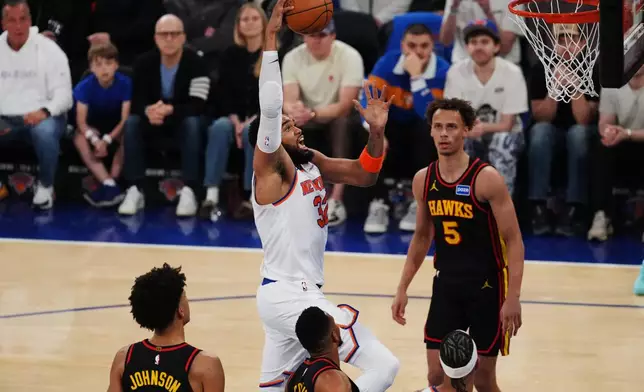 New York Knicks' Karl-Anthony Towns (32) drives past Atlanta Hawks' Dyson Daniels (5) during the first half in Game 1 of a first-round NBA playoffs basketball series, Saturday, April 18, 2026, in New York. (AP Photo/Frank Franklin II)