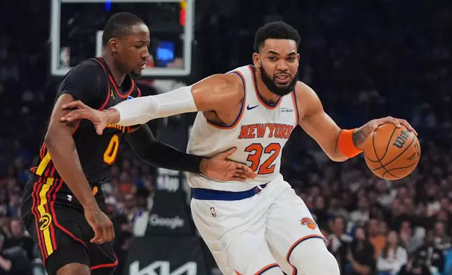 New York Knicks' Karl-Anthony Towns (32) drives past Atlanta Hawks' Jonathan Kuminga (0) during the first half in Game 1 of a first-round NBA playoffs basketball series, Saturday, April 18, 2026, in New York. (AP Photo/Frank Franklin II)