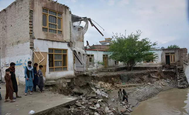 Residents inspect a building that partially collapsed due to heavy flooding in Jalalabad, Afghanistan, Saturday, April 4, 2026. (AP Photo/Wahidullah Kakar)