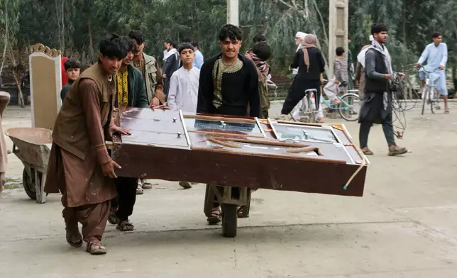 Residents carry furniture in a wheelbarrow as they clear an area damaged by heavy flooding in Jalalabad, Afghanistan, Saturday, April 4, 2026. (AP Photo/Wahidullah Kakar)
