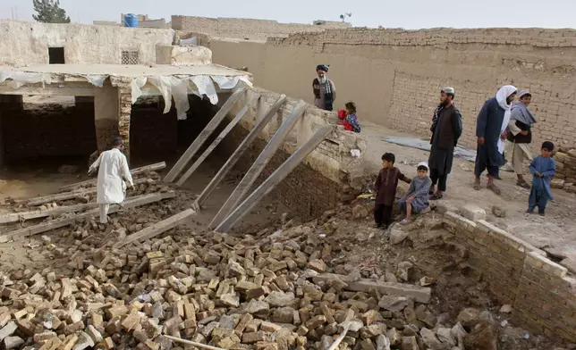 Locals inspect a damaged house following floods, landslides and thunderstorms in Kandahar province, Afghanistan, Sunday, March 29, 2026. (AP Photo/Sibghatullah)