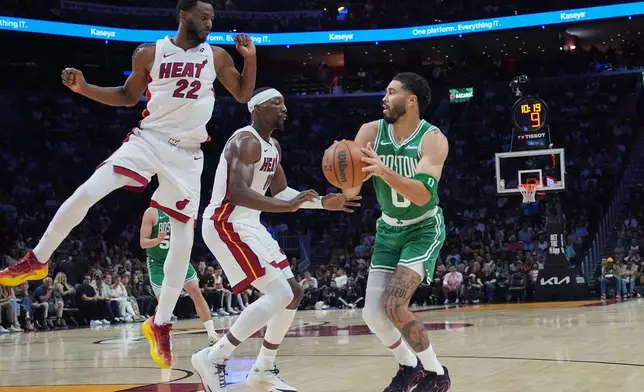 Miami Heat forward Andrew Wiggins (22) and center Bam Adebayo, center, defend Boston Celtics forward Jayson Tatum (0) during the first half of an NBA basketball game, Wednesday, April 1, 2026, in Miami. (AP Photo/Lynne Sladky)