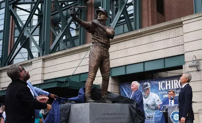Former Seattle Mariners Edgar Martinez, left, and Ken Griffey Jr., second from left, look on with right fielder Ichiro Suzuki, right, at the broken bat of Ichiro's statue during its unveiling outside of T-Mobile Park, Friday, April 10, 2026, in Seattle. (AP Photo/Lindsey Wasson)