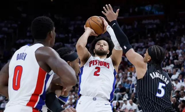 Detroit Pistons guard Cade Cunningham (2) takes a shot against Orlando Magic forward Paolo Banchero (5) as Pistons center Jalen Duren (0) helps defend during the first half in Game 2 of a first-round NBA basketball playoffs series Wednesday, April 22, 2026, in Detroit. (AP Photo/Duane Burleson)
