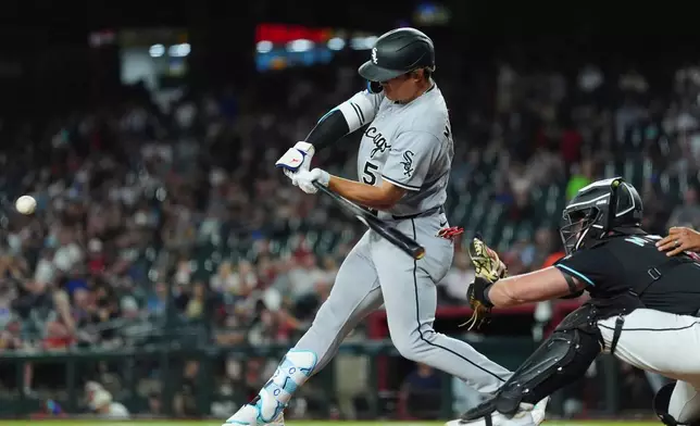 Chicago White Sox's Munetaka Murakami (5) starts his swing on a single as Arizona Diamondbacks catcher James McCann reaches for the ball during the fifth inning of a baseball game, Wednesday, April 22, 2026, in Phoenix. (AP Photo/Ross D. Franklin)