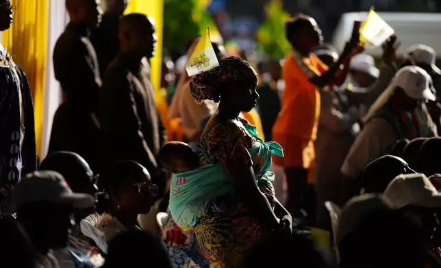 A woman with her child attends Pope Leo XIV's meeting with University students and professors at the Catholic University of Central Africa, in Yaounde Cameroon, Friday, April 17, 2026. (AP Photo/Andrew Medichini)