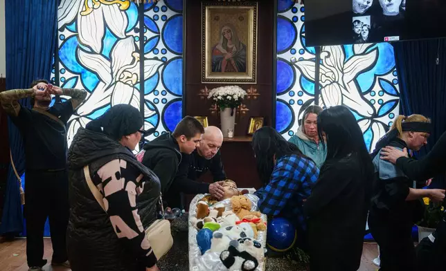Family members pay their final respects to 8-year-old Bohdan Serhiiev who was killed in a Russian drone attack, during a farewell ceremony in Cherkasy, Ukraine, Thursday, April 16, 2026. (AP Photo/Evgeniy Maloletka)