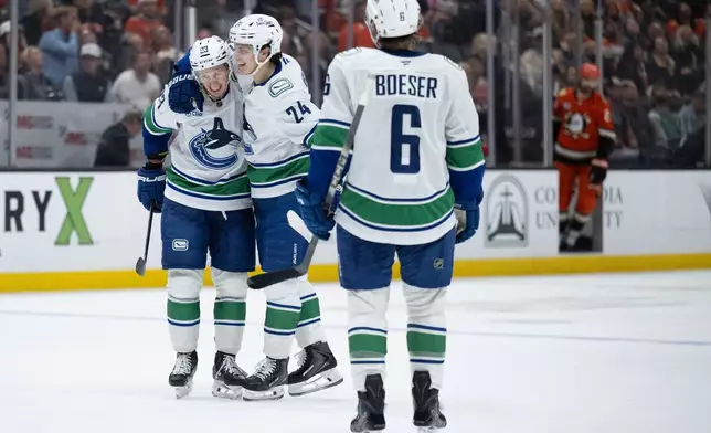 Vancouver Canucks center Marco Rossi, left, celebrates his game-winning overtime goal with defenseman Zeev Buium, center, in an NHL hockey game against the Anaheim Ducks, Sunday, April 12, 2026, in Anaheim, Calif. (AP Photo/Kyusung Gong)