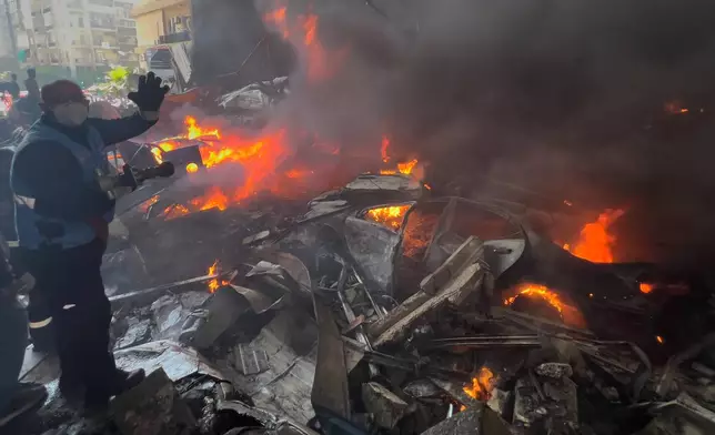 A rescue worker extinguishes burning cars at the site of an Israeli airstrike in central Beirut, Lebanon, Wednesday, April 8, 2026. (AP Photo/Hussein Malla)