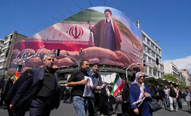 Government supporters walk past a billboard depicting Iran's Supreme Leader Mojtaba Khamenei as they gather to mark the 40th day since the killing of his father, slain Supreme Leader Ayatollah Ali Khamenei, in Tehran, Iran, Thursday, April 9, 2026. (AP Photo/Vahid Salemi)