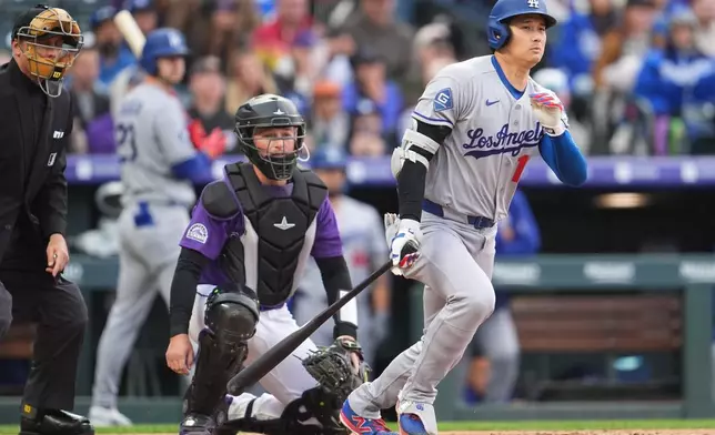 Los Angeles Dodgers two-way player Shohei Ohtani, right, grounds out as Colorado Rockies catcher Hunter Goodman, center, and home plate umpire Dan Issogna, left, look on in the third inning of a baseball game Saturday, April 18, 2026, in Denver. (AP Photo/David Zalubowski)