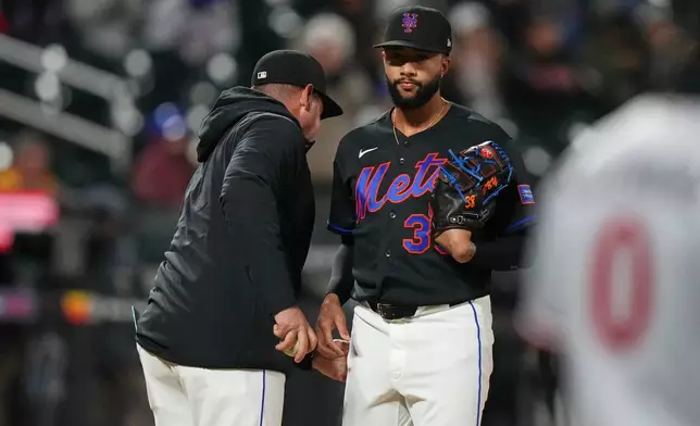 New York Mets pitcher Devin Williams, right, hands the ball to manager Carlos Mendoza as he leaves during the ninth inning of a baseball game against the Minnesota Twins Tuesday, April 21, 2026, in New York. (AP Photo/Frank Franklin II)