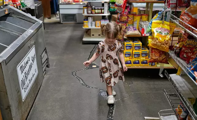 Oakley Wooten, 2, walks on a crack that formed inside the historic Nelson's Old Riverton Store about 20 years ago and was subsequently patched and painted to resemble Route 66 which passes by outside in Riverton, Kan., Tuesday, Nov. 18, 2025. (AP Photo/Jeff Roberson)