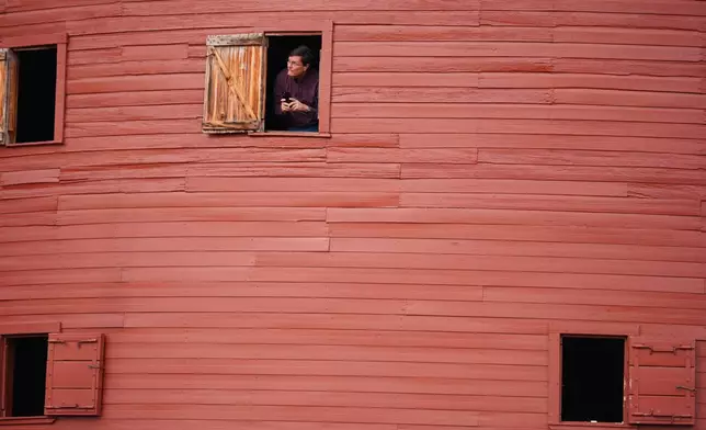 David Dobbins, of Ankeny, Iowa, peeks out a window at the Round Barn along Route 66 in Arcadia, Okla., during a stop on his Route 66 trip with his wife, Robin, Wednesday, Nov. 19, 2025. (AP Photo/Julio Cortez)