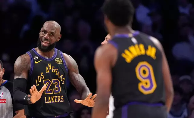 Los Angeles Lakers forward LeBron James, left, talks to guard Bronny James during the first half of an NBA basketball game against the Cleveland Cavaliers, Tuesday, March 31, 2026, in Los Angeles. (AP Photo/Mark J. Terrill)
