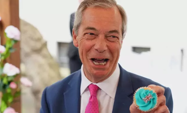 Nigel Farage leader of Reform UK holds up a cup cake with the union flag as he joins supporters for tea after a press conference in London, Thursday, April 2, 2026. (AP Photo/Kirsty Wigglesworth)