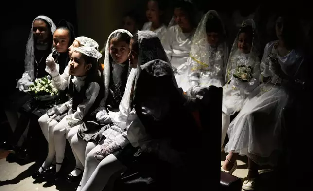 Girls wait inside a church for their Children's Holy Thursday procession during Holy Week in Tunja, Colombia, Thursday, April 2, 2026. (AP Photo/Fernando Vergara)