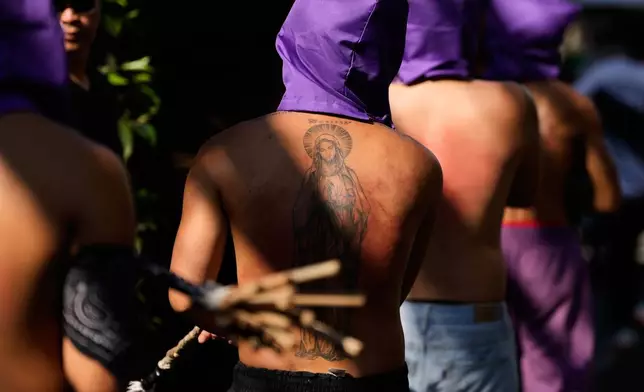 A hooded Filipino flagellant, with a Virgin Mary tattoo, whips his back along a street as part of Maundy Thursday rituals to atone for sins or fulfill vows for an answered prayer on April 2, 2026 at Mandaluyong city, Philippines as they practice bizarre lenten rituals frowned upon by the church in this predominantly Roman Catholic country. (AP Photo/Aaron Favila)