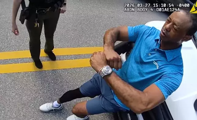 In this image taken from police body camera video released by the Martin County, Fla., Sheriff's Office, golfer Tiger Woods performs a field sobriety test for sheriff's deputies following a car crash in Jupiter Island, Fla., Friday, March 27, 2026. (Martin County Sheriff's Office via AP)