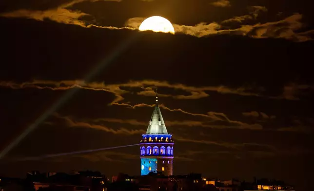 A full moon rises behind Galata Tower, in Istanbul, Turkey, Thursday, April 2, 2026. (AP Photo/Emrah Gurel)