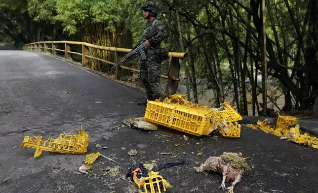 Soldiers stand next to a truck carrying chickens that was set on fire by dissident factions of the former FARC rebels in Jamundi, Colombia, Monday, April 27, 2026. (AP Photo/Santiago Saldarriaga)