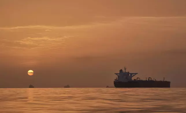 The sun rises behind tankers anchored in the Strait of Hormuz off the coast of Qeshm Island, Iran, Saturday, April 18, 2026. (AP Photo/Asghar Besharati)