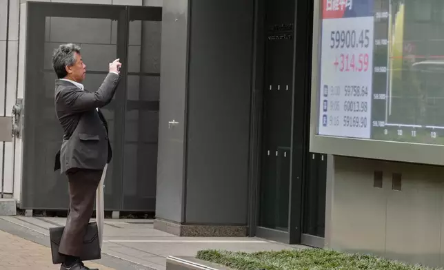 A person takes a photo of an electronic stock board showing Japan's Nikkei index outside a securities firm Thursday, April 23, 2026, in Tokyo. (AP Photo/Eugene Hoshiko)