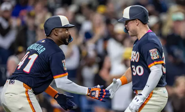 San Diego Padres' Miguel Andujar, left, celebrates a home run by Gavin Sheets (30) in the fifth inning of a baseball game against the Colorado Rockies, Friday, April 10, 2026, in San Diego. (AP Photo/Tony Ding)