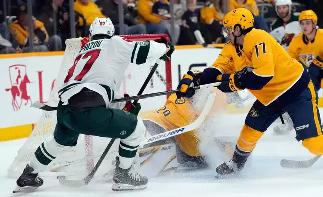 Nashville Predators right wing Luke Evangelista (77) keeps Minnesota Wild left wing Kirill Kaprizov (97) away from the net during the first period of an NHL hockey game Saturday, April 11, 2026, in Nashville, Tenn. (AP Photo/Mark Humphrey)