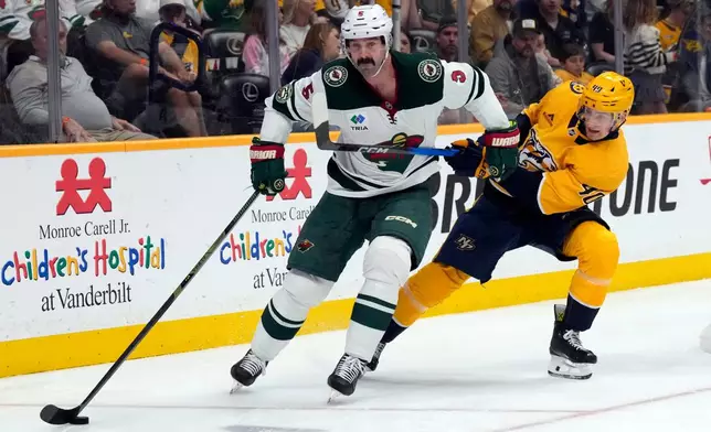 Minnesota Wild defenseman Jake Middleton (5) moves the puck away from Nashville Predators center Fedor Svechkov (40) during the second period of an NHL hockey game Saturday, April 11, 2026, in Nashville, Tenn. (AP Photo/Mark Humphrey)